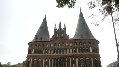 Tilt-up-shot-of-historic-Holsten-Gate-with-exploring-people-during-sunny-day-in-Germany