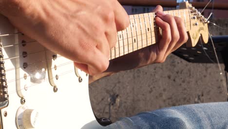 Primer-Plano-De-Un-Joven-Guitarrista-Tocando-La-Guitarra-Eléctrica-En-Un-Concierto-Al-Aire-Libre-El-Día-De-La-Música