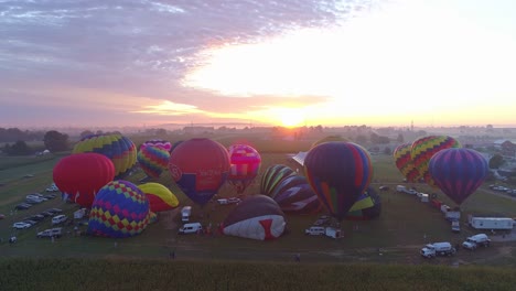 Vista-Aérea-De-Un-Lanzamiento-Matutino-De-Globos-Aerostáticos-En-Un-Festival-De-Globos-Desde-El-Llenado-Hasta-El-Despegue-Visto-Por-Un-Dron