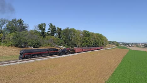 Eine-Luftaufnahme-Von-Zwei-Dampflokomotiven-Aus-Norfolk-Und-Western,-Die-Auf-Zwei-Gleisen-In-Der-Landschaft-Auffahren