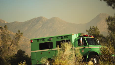 Firefighting-helicopter-landing-behind-fire-truck,-tackling-California-bush-fire