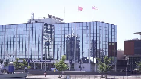 Flags-fly-on-top-of-the-building-of-the-Chamber-of-Commerce-in-Amsterdam,-the-Netherlands,-on-a-bright-sunny-day