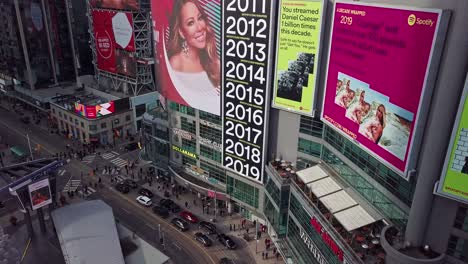 Spotify-Ads-on-Huge-Digital-Billboards,-Wide-Aerial-Rise-and-Tilt-Down