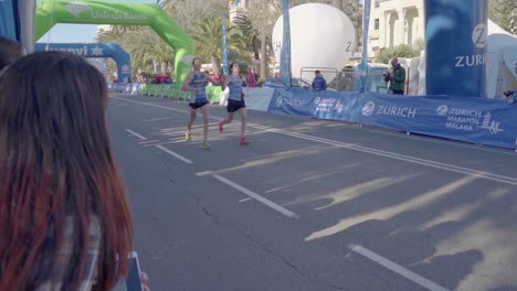 Marathon-runners-running-towards-the-finish-line,-crowd-watching-at-the-side