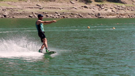 Hombre-Disfrutando-Del-Esquí-Acuático-Deslizándose-Con-Velocidad-En-La-Superficie-Del-Agua-En-El-Lago-En-Albufeira-Da-Barragem-Do-Ermal,-Portugal---Tiro-Ancho