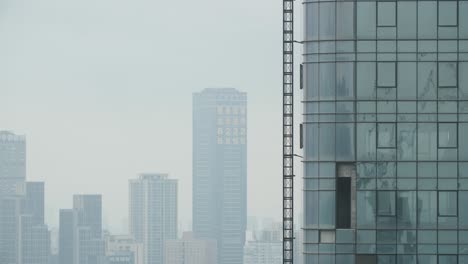 Edificios-De-Gran-Altura-Hechos-De-Acero-Y-Vidrio-Con-Neblina-De-Contaminación-Del-Aire-De-Cenizas-De-Carbón-En-La-Distancia,-Toma-De-Mano