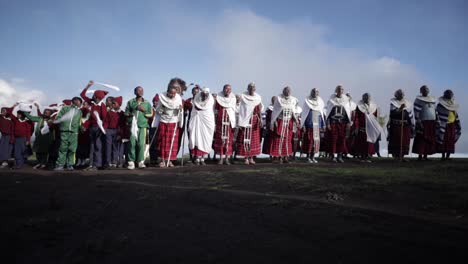 A-group-of-villagers-and-school-kids-from-the-Maasai-Massai-Tribe-are-dancing-and-jumping-for-a-cultural-traditional-ceremony-in-their-traditional-clothing-in-Tanzania-Africa---slowmotion-low-shot