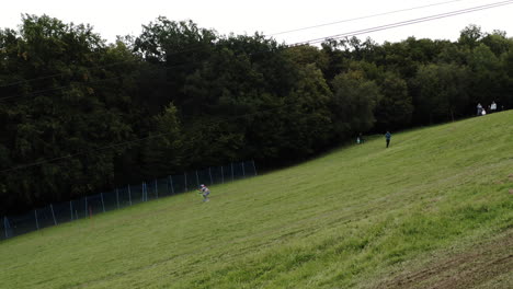 Multitud-De-Personas-Ven-A-Un-Competidor-Esquiando-En-Una-Competencia-De-Esquí-De-Hierba,-Deporte-Alpino-De-Verano