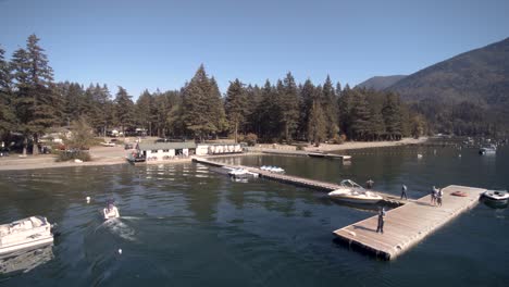 Drohnen-4K-Aufnahmen-Von-Bootsverleih,-Jet-Ski,-Angedockten-Menschen,-Die-An-Einem-Sonnigen-Tag-Freizeitbeschäftigung-Haben,-Clam-Cultus-See,-Umgeben-Von-Bergen-Im-Provinzpark-Von-British-Columbia,-Kleinunternehmen,-Reisewirtschaft