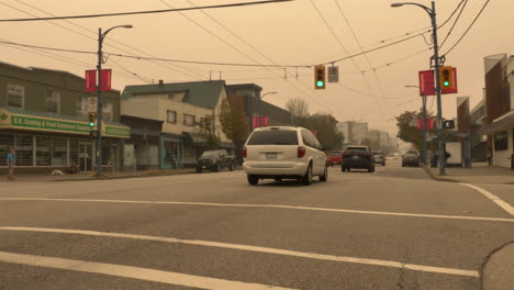 Toma-A-Nivel-Del-Suelo-De-Vehículos-Conduciendo-En-La-Calle-West-Hastings-En-Vancouver,-Bc-Bajo-El-Cielo-Sombrío-Debido-Al-Humo-De-Los-Incendios-Forestales-En-América-Del-Norte