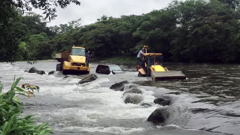 Concepto-De-Fuertes-Lluvias-E-Inundaciones,-Automóvil-Suv-Atascado-En-El-Río-De-Marea,-Remolcado-Por-Máquinas-De-Construcción