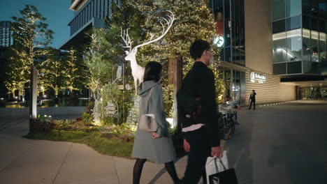 Personas-Con-Máscaras-Caminando-Por-Un-árbol-De-Navidad-Ornamental-Y-Renos-Fuera-De-Un-Edificio---Cámara-Lenta