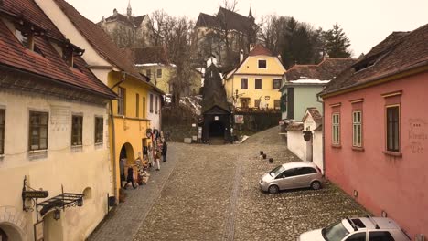 Vista-Panorámica-De-Algunas-Tiendas-De-Souvenirs-Y-La-Entrada-Del-Puente-De-Madera-Cubierto-En-Sighisoara-Con-La-Iglesia-En-La-Colina-Al-Fondo