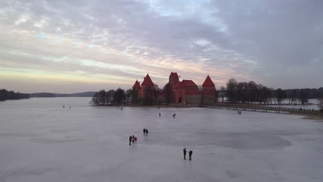 Antena:-Volando-Hacia-El-Castillo-De-La-Isla-Trakai-Sobre-Un-Lago-Congelado-Con-Gente-Caminando-Sobre-El-Hielo