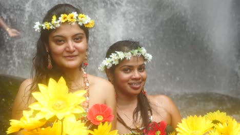 Portrait-of-two-Cambodian-girls-holding-flowers-with-waterfall-at-background