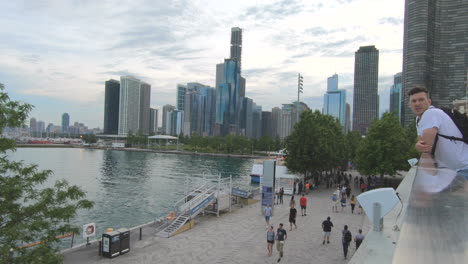 Editorial,-smooth-zoom-in-shot,-view-of-couple-enjoying-and-watching-waterfront-view-,-lake-of-Michigan,-at-Navy-Pier-Chicago,-buildings,-skyscrapers,-tourists,-people-and-beautiful-sky-and-clouds