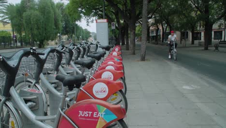 Menschen,-Die-Auf-Dem-Radweg-An-Sevici-Fahrrädern-Vorbei-In-Sevilla,-Spanien,-Slowmo-Fahren