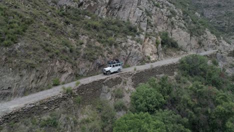 Toma-Aérea-De-Un-Jeep-Willis-Con-Un-Turista-En-Una-Calle-Angosta-En-Real-De-Catorce,-San-Luis-Potosi,-México