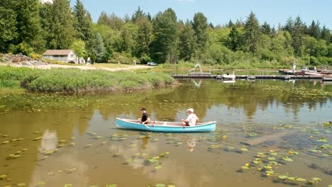 Dos-Hombres-En-Canoa-En-Un-Lago-Con-Lirios