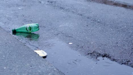 Una-Botella-De-Perrier-Y-Una-Taza-De-Basura-Una-Alcantarilla-Lluviosa