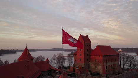 AERIAL:-Reveal-Shot-of-Waving-Flag-with-White-Vytis-on-a-Red-Field