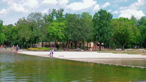 Parque-De-La-Ciudad-Del-Lago-Városligeti,-Al-Otro-Lado-Del-Parque,-Personas-Que-Cruzan-La-Mini-Humedad,-Continuar-Tiro-1