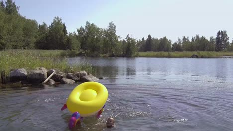 Kinder-In-Den-Sommerferien-Haben-Spaß-Im-Wasser,-Junge-Reitet-Und-Fällt-Vom-Aufblasbaren-Einhorn