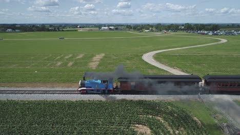 Luftaufnahme-Eines-Thomas-The-Tank-Engine-Mit-Passagierwagen,-Die-Entlang-Der-Amischen-Landschaft-Schnaufen