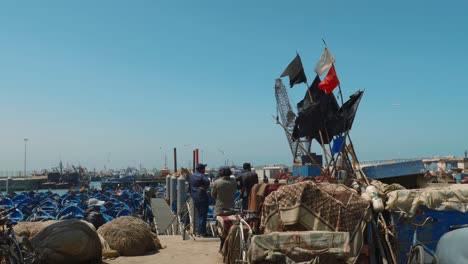 Moroccan-people-looking-at-the-harbor-with-blue-boats-in-Essaouira