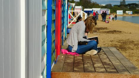 Mädchen-Liest-Buch-In-Brighton-Bathing-Boxes,-Melbourne,-Australien