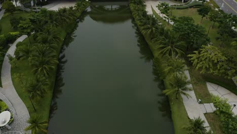 Aerial-view-flying-over-beautiful-landscaping-with-pedestrian-bridge-and-large-Sala-flower-in-a-new-luxury-development,-Thu-Thiem,-district-2,-Ho-Chi-Minh-City,-Vietnam