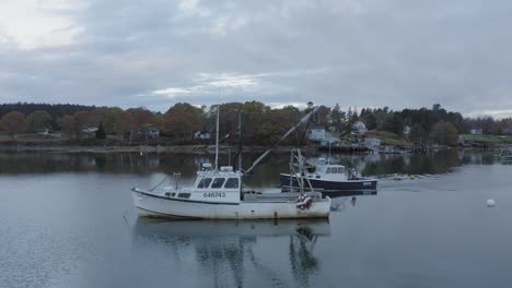 Fishing-boat-passes-moored-boat-within-bay-at-dawn-4K