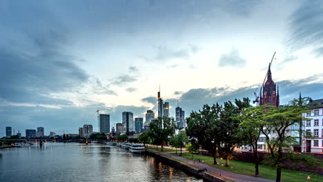 Timelapse-La-Vista-Desde-El-Río-Principal-Hasta-El-Horizonte-De-La-Ciudad-De-Frankfurt-Al-Atardecer,-Hesse,-Alemania,-Julio-De-2018