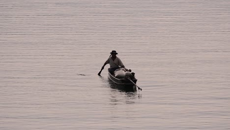 Fisherman-silhouetting-as-he-is-casting-and-drawing-his-net-in-the-River-before-dark,-in-slow-motion