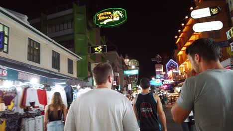 Escenas-De-Mano-De-Los-Turistas-Caminan-Por-La-Calle-Khao-San-En-La-Noche-Famosa-Que-Cada-Año-Turistas-De-Muchos-Países-Venían-A-Visitar-En-Bangkok,-Tailandia