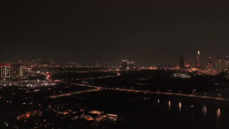 Un-Dron-Descendiente-De-Eiree-Disparó-Sobre-El-Río-Saigón-En-La-Ciudad-De-Ho-Chi-Minh,-Vietnam-De-Noche,-Mostrando-El-Horizonte-De-La-Ciudad-Y-El-Puente-Al-Distrito-Dos