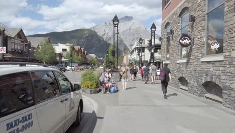 Vista-De-La-Calle-Del-Paisaje-De-La-Avenida-Principal-De-La-Calle-Local-En-Banff-Con-Muchas-Personas-En-El-Camino-A-Pie-En-Verano-En-La-Ciudad-De-Banff,-Canadá