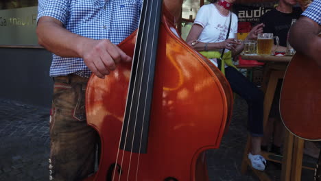 Eine-Gruppe-österreichischer-Männer-Hält-Musikinstrumente-Mit-Biergläsern-Auf-Dem-Tisch-Und-Menschen-Im-Hintergrund