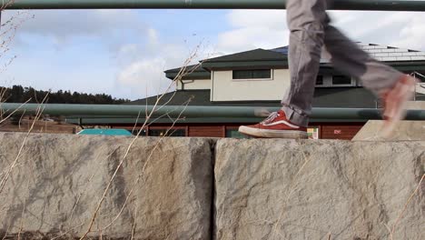 Hombre-Camina-A-Través-De-Una-Pared-Baja-De-Cemento-En-Un-Par-De-Zapatillas-Vans-Rojas