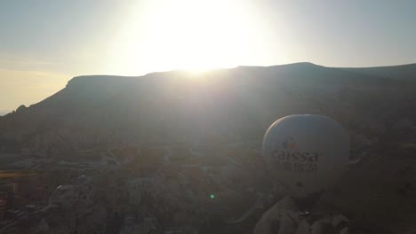 Aerial-view-of-hot-air-balloons-flying-over-a-mountain-landscape,-Cappadocia,-Turkey,-during-sunset