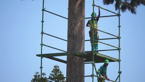 Timelapse-of-workers-building-scaffolding-around-a-tower,-set-against-a-clear-blue-sky