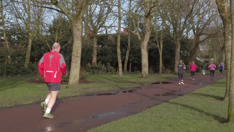 Active-fitness-group-jogging---walking-in-wet-rainy-park-in-slow-motion-push-in-slow