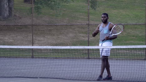 Young-sportsman-with-a-racquet-in-hand-wiping-sweat-off-his-face-while-playing-a-tennis