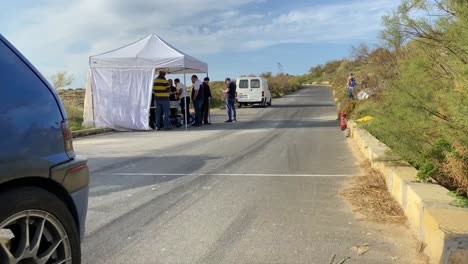 Maßgeschneidertes-Blaues-Auto-Fährt-Am-Boxenstopp-Mit-Weißem-Zelt-Am-Straßenrand-Auf-Dem-Hügel-In-Imtahleb,-Malta-Vorbei-–-Nahaufnahme