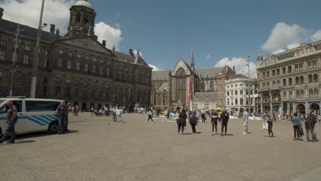 Gente-Caminando-Por-La-Histórica-Plaza-Dam-En-Amsterdam-En-El-Verano