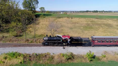 Aerial-View-of-a-Antique-Steam-Engine-Puffing-along-Pulling-Antique-Passenger-Cars-Through-Amish-Farm-Lands-on-a-Sunny-Autumn-Day-as-Seen-by-a-Drone