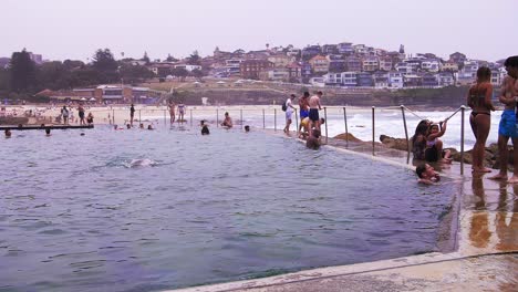 Turistas-Disfrutando-De-Un-Baño-Y-De-La-Vista-De-La-Playa-Bronte-En-Australia-Con-La-Pacífica-Ciudad-De-Sydney-En-La-Distancia---Cámara-Lenta