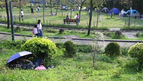 People-rest-and-enjoy-their-evening-outdoors-at-a-park-while-social-distancing-still-in-place-due-to-the-Coronavirus-epidemic,-officially-known-as-Covid-19,-in-Hong-Kong