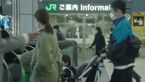 Personas-Con-Máscaras-Tocando-Teléfonos-Inteligentes-Para-Pasar-Por-Las-Puertas-Automáticas-De-Boletos-En-La-Estación-Shinagawa-Jr-En-Tokio---Plano-Medio,-Cámara-Lenta