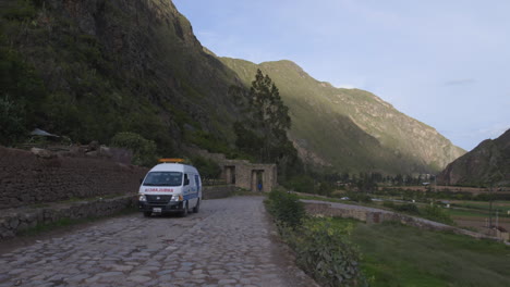 Ein-Krankenwagen-Fährt-Eine-Kopfsteinpflasterstraße-Entlang,-Die-Nach-Ollantaytambo-Im-Heiligen-Tal-Perus-Führt